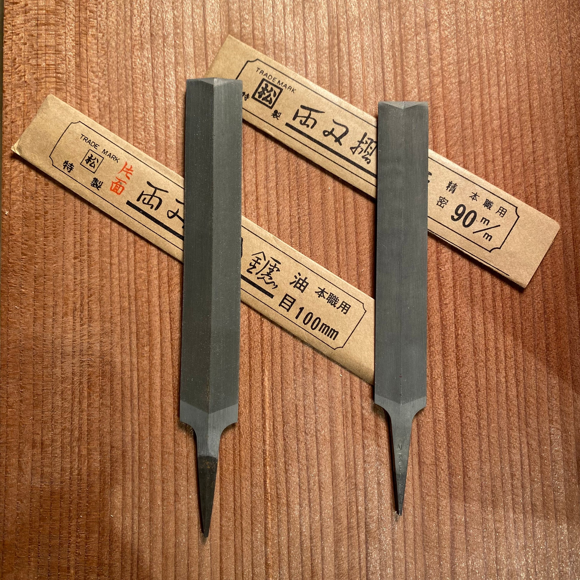 Two files on a wooden surface with their paper sheathes
