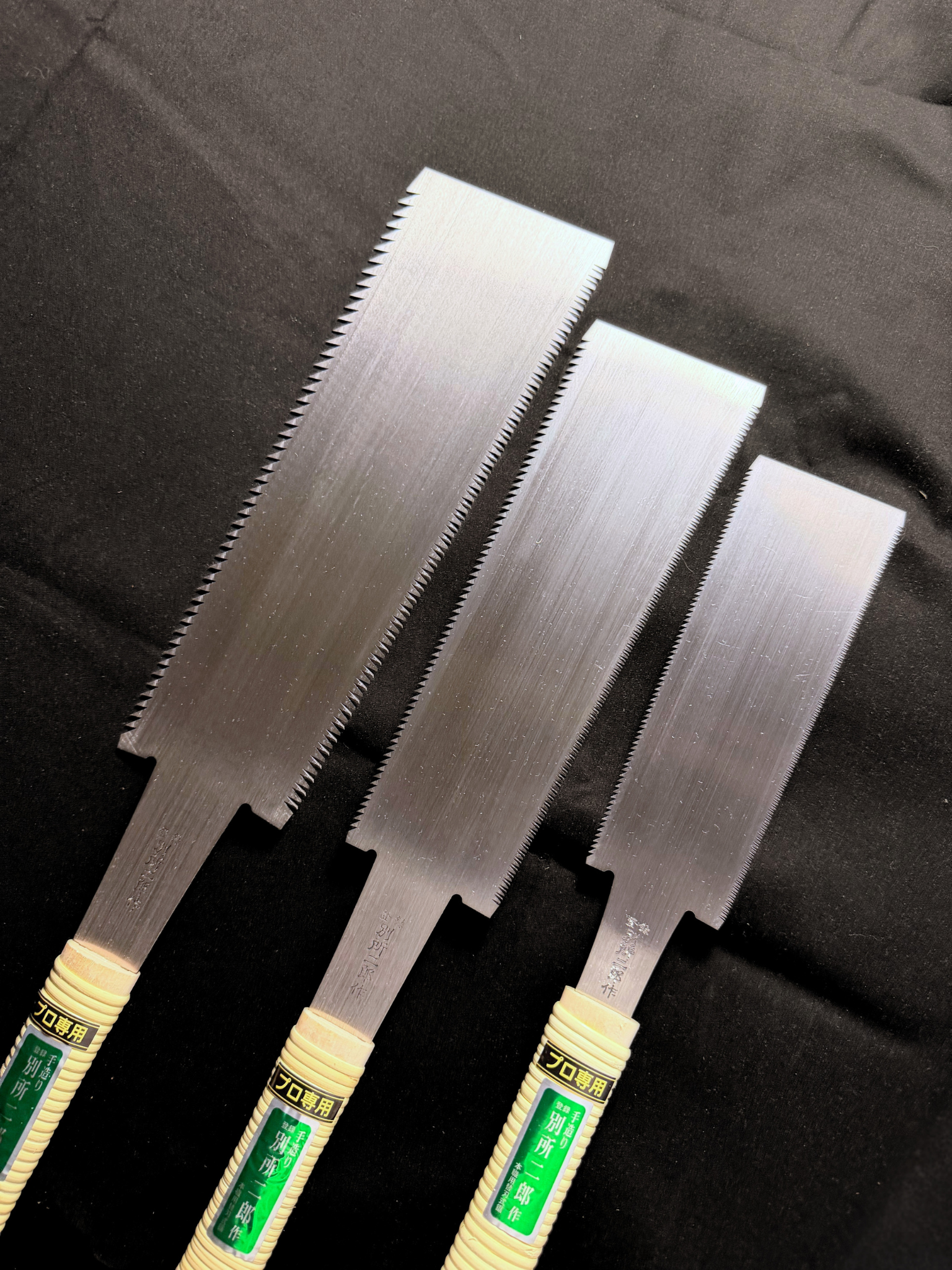A picture of three ryoba saws on a black background